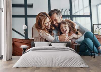 Happy young family smiling and embracing  Wall mural