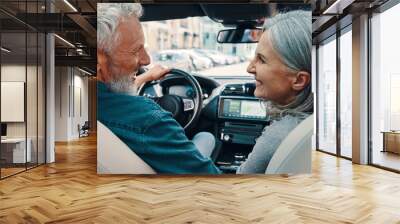 Rear view of active senior couple enjoying car ride while sitting on front seats of the car Wall mural