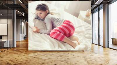 Cute little girl working with tablet computer lying in bed Wall mural