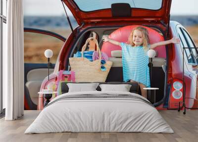 Portrait of a little girl sitting in the trunk of a car Wall mural