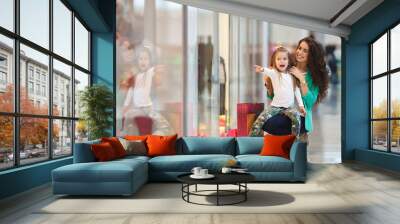 Young mother and her daughter doing shopping together Wall mural