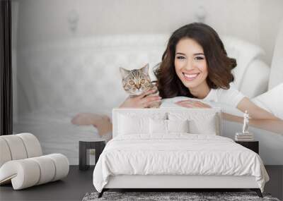 Young woman playing on the bed with the cat Wall mural