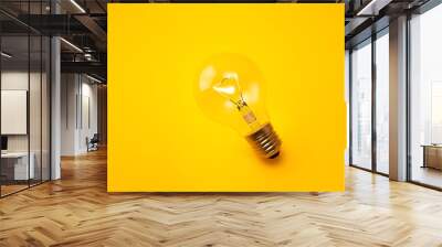 Glowing light bulb isolated on a bright yellow background. Wall mural