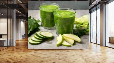 Green juice and ingredients in glass on grey background Wall mural