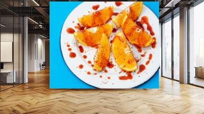 Orange slices with chilli powder and chamoy on colorful background Wall mural