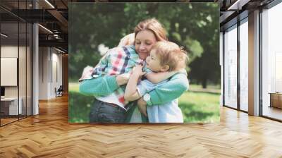 Family happiness! Happy mother tenderly embracing his two sons children in summer park Wall mural