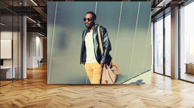 Portrait of stylish young african man model posing wearing black rock leather jacket with bag on city street background Wall mural