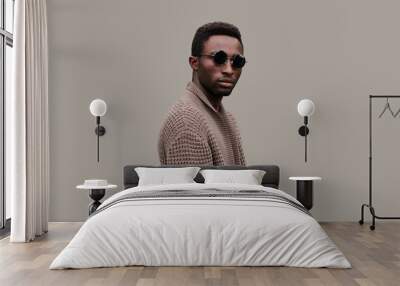 Portrait of stylish young african man model wearing knitted cardigan isolated on gray background Wall mural