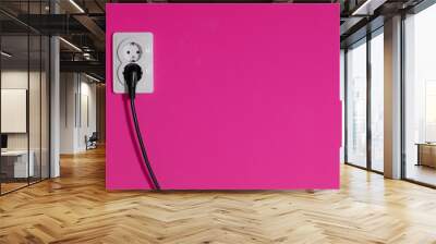 Cable connected into a power outlet on a pink wall Wall mural