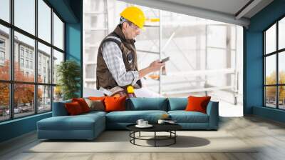 Builder or contractor using a mobile phone on site Wall mural