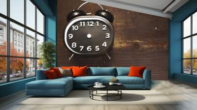 a black and white vintage alarm clock laying on a wooden background Wall mural