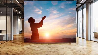 Silhouette of a man are praying over sunset background Wall mural