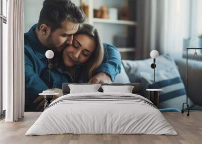 Loving husband man comforting upset wife while hugging her and sitting on the sofa at home Wall mural