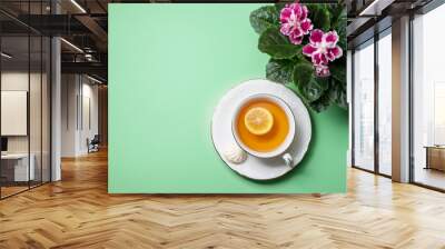 Flowering Saintpaulias, commonly known as African violet and a cup of tea with lemon close-up. Composition for Valentine's Day, birthday. Wall mural