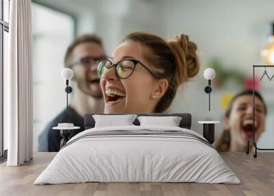 A cheerful young woman laughing heartily with colleagues, promoting a positive and fun office culture Wall mural