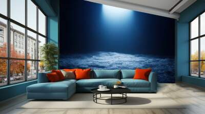 A dark cave illuminated by a single light source from the ceiling, casting a soft glow on the rough ground. The cave represents solitude and mystery. Wall mural