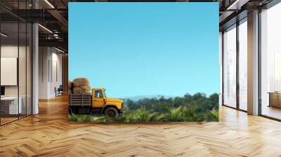 A vibrant yellow truck is captured transporting hay bales across a lush green field under an expansive, clear blue sky, invoking a sense of rural tranquility. Wall mural