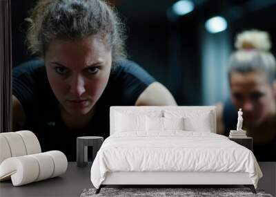 Two women are deeply engaged in an intense workout session, showcasing determination and athletic prowess in a dimly lit gym setting filled with focus and drive. Wall mural