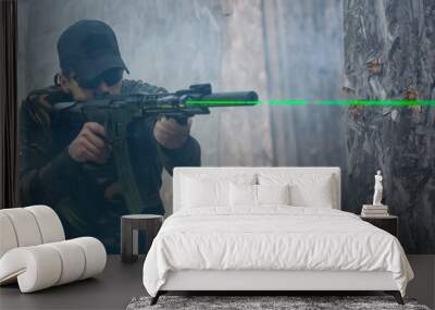 Army soldier in action aiming at weapon laser sight optics. Shooting and weapons. Outdoor shooting range Wall mural