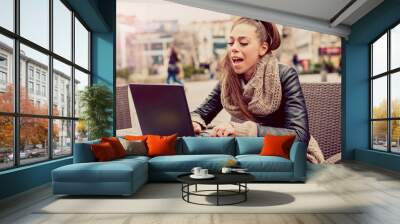 Beautiful young student using laptop at outdoor cafe / Portrait of beautiful smiling woman sitting in a cafe with laptop outdoor Wall mural