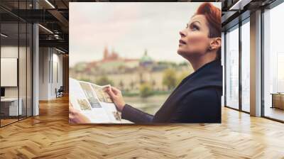 Female tourist looking at city guide Wall mural