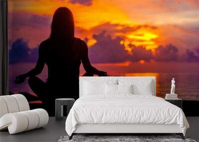 Woman meditating, relaxing in yoga pose at sunset, zen meditation. Silhouette in lotus pose. Mind body spirit concept Wall mural