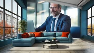 Happy smiling middle aged professional business man company executive ceo manager wearing blue suit sitting at desk in office working on laptop computer. Portrait. Generative AI. Wall mural