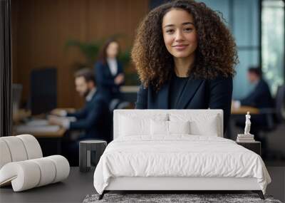 Portrait of a confident businesswoman with arms crossed in a formal office setting. Professional headshot with blurred colleagues working in the background Wall mural