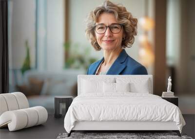 Portrait of a smiling middle-aged businesswoman confidently stands with arms crossed in a modern, brightly lit office space, showcasing leadership and professionalism Wall mural