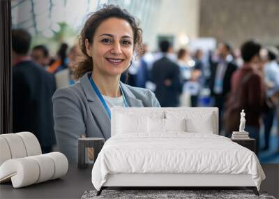 Smiling businesswoman with lanyard standing with arms crossed at a networking event in a conference hall. Corporate networking and career development concept Wall mural