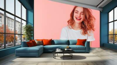 Vivacious Young Woman Laughing. Exuberant young lady in white tee, joyfully laughing on a pink background. Wall mural