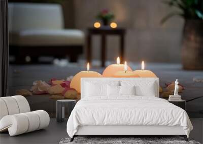 Five lit candles on a stone floor surrounded by petals and a blurred background. Wall mural