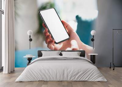 Man using smartphone blank screen frameless modern design while lying on the sofa in home interior Wall mural