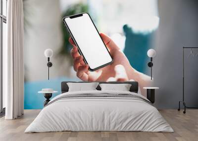 Man using smartphone blank screen frameless modern design while lying on the sofa in home interior Wall mural