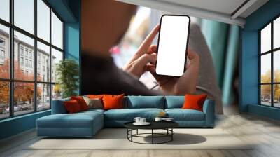 Man using smartphone blank screen frameless modern design while sitting on the chair in home interior Wall mural