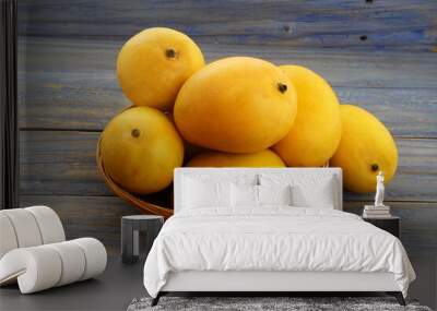 fresh ripe yellow mango fruit in basket isolated on wood background Wall mural