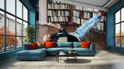 Bearded hipster man relax and reading book lies on the floor Wall mural