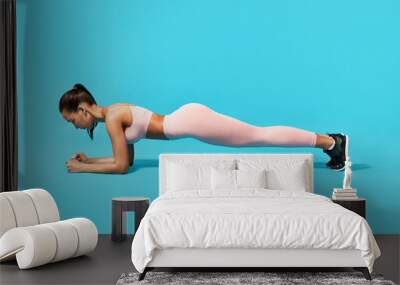 Fitness young woman doing plank exercise Wall mural