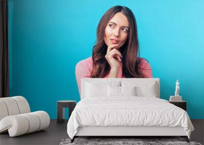 Portrait of thoughtful wondering woman looking sideways isolated over blue background Wall mural