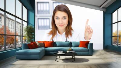 Portrait of young female doctor with a raised finger in hospital Wall mural