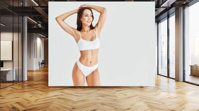 Smiling sporty woman in white underwear posing on studio background with copy space Wall mural