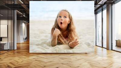 Surprised cute little blonde girl relax on the beach on summer holiday Wall mural