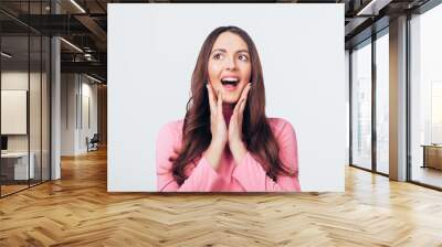 Young happy and surprised woman looking left and holds cheeks by hand isolated on white backround Wall mural