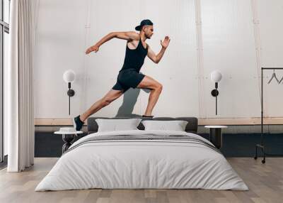 Young man runner running along wall with copy space Wall mural