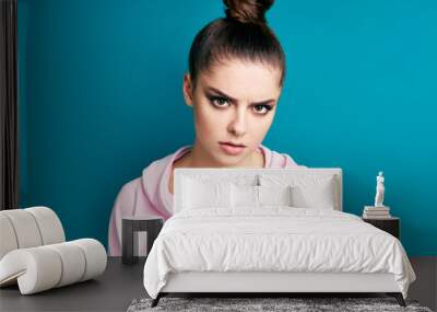 Young serious angry woman close up portrait on blue background Wall mural