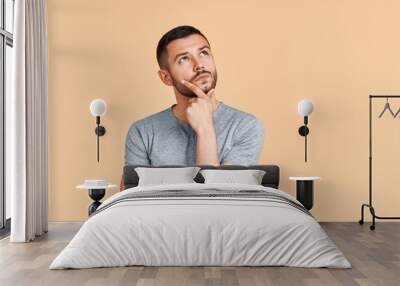 Young thoughtful man thinking and looking aside on copy space isolated on yellow background Wall mural