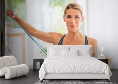 Attractive woman exercising with a power band at home Wall mural