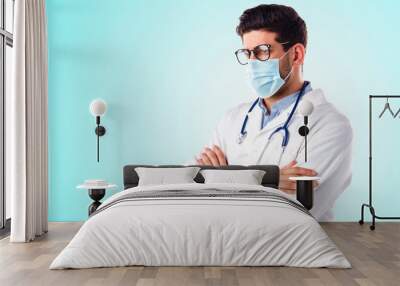 Male doctor wearing face mask while standing at isolated background Wall mural