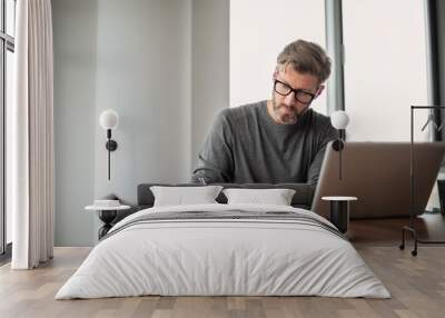 Middle aged businessman using laptop at the office Wall mural