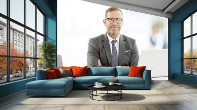 Middle aged businessman with laptop. Portrait of mature senior male agent wearing shirt and tie while sitting at desk and working on laptop at the office.  Wall mural